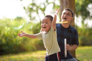 Un enfant et un adulte jouant avec des bulles.