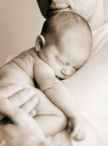 Very young baby sleeping on parent's shoulder.