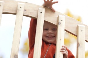 RRCbridge Jeune enfant qui sourit, regardant à travers les poteaux d’une balustrade d’escalier.
