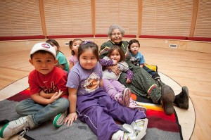 Group of children sitting on a mat with an Elder.
