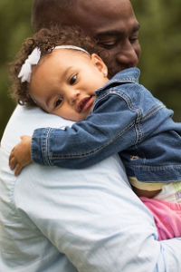 Young child held by father.