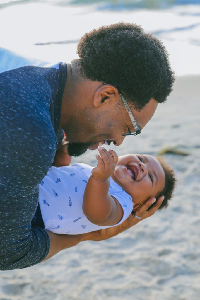 Adult leaning over to gaze at baby's face.